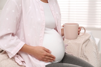 Photo of Pregnant woman drinking tea at home, closeup