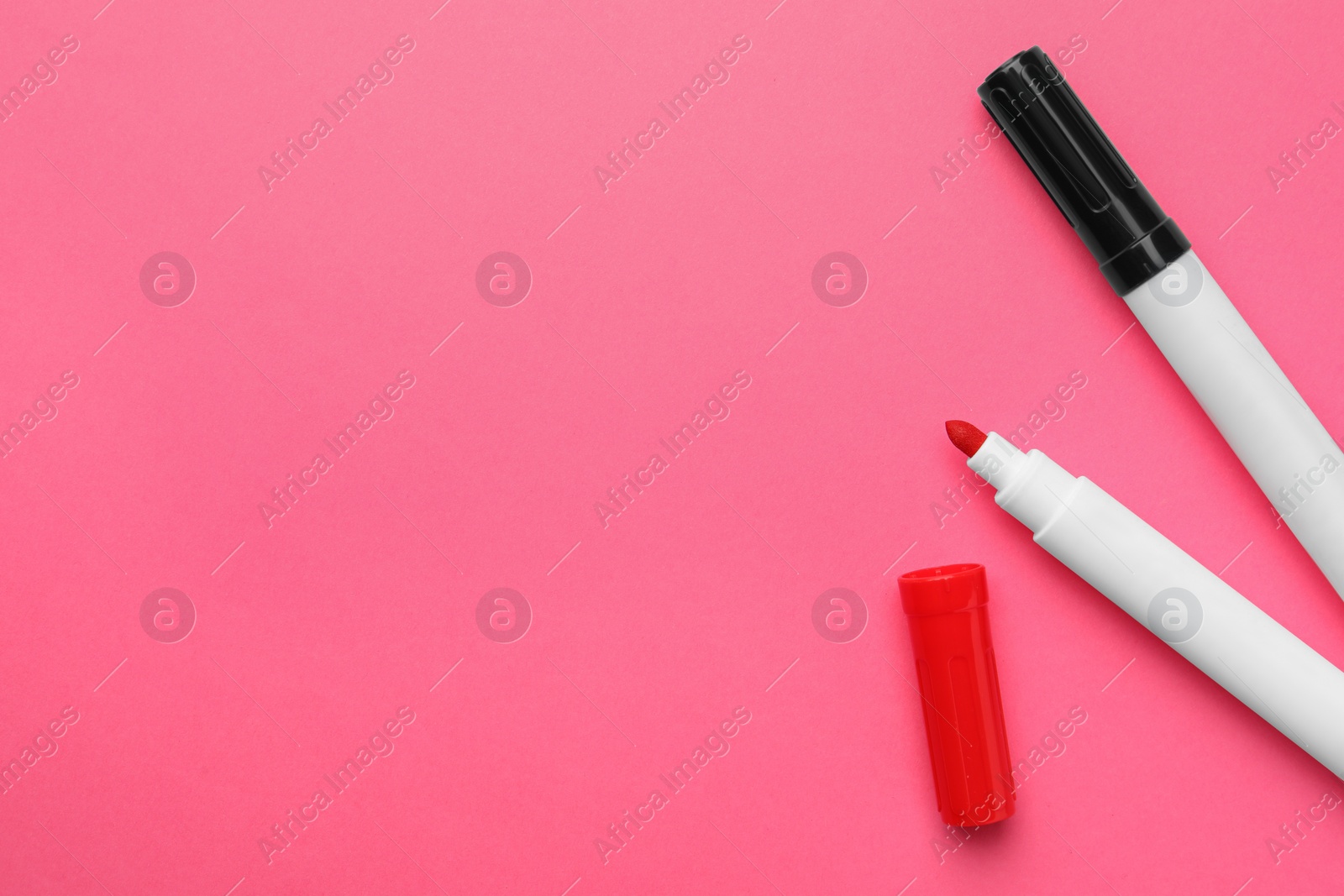 Photo of Bright color markers on pink background, flat lay. Space for text