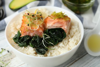 Photo of Tasty salmon with rice and spinach on white wooden table, closeup