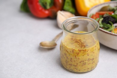 Photo of Tasty vinegar based sauce (Vinaigrette) in jar on light table, closeup. Space for text