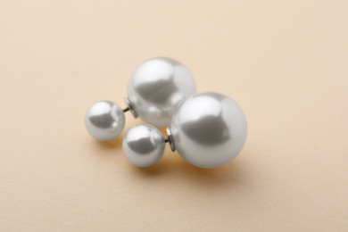 Photo of Elegant earrings with pearls on beige background