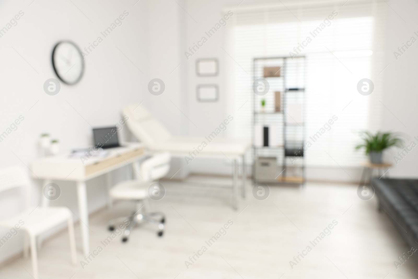 Photo of Blurred view of modern medical office with doctor's workplace and examination table in clinic