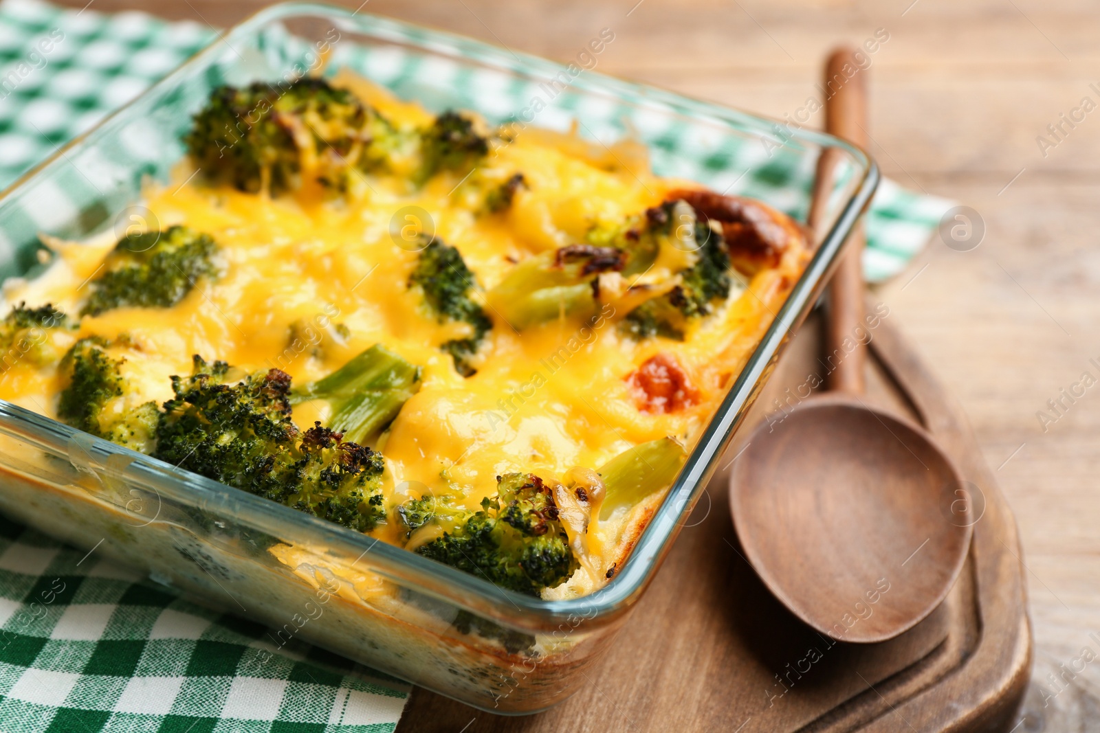 Photo of Tasty broccoli casserole in baking dish on wooden table, closeup