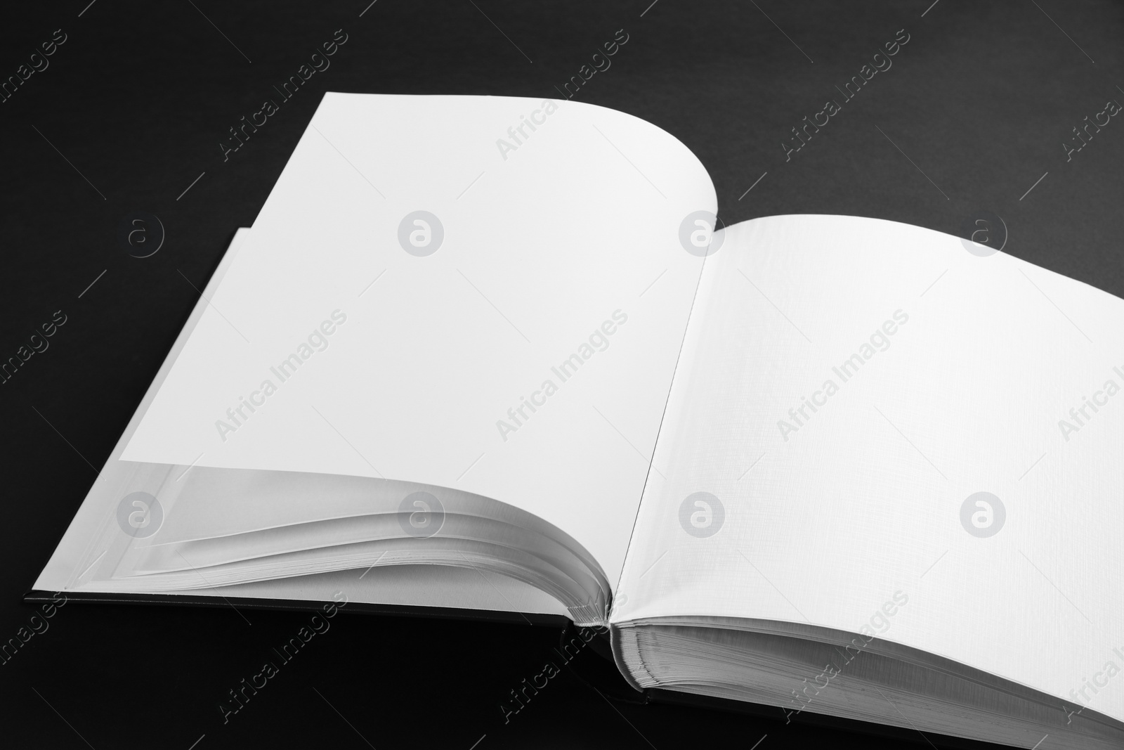 Photo of One open photo album on black background, closeup. Space for text