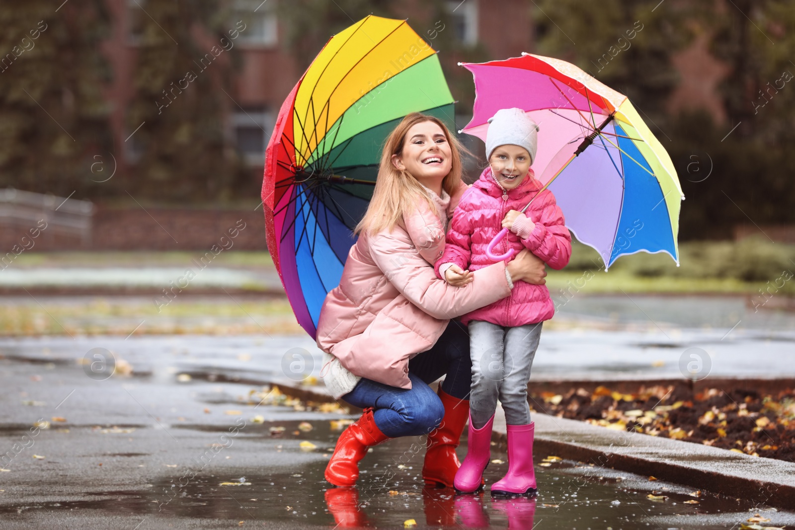 Photo of Mother and daughter with umbrellas taking autumn walk in city on rainy day