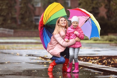 Photo of Mother and daughter with umbrellas taking autumn walk in city on rainy day