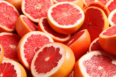 Photo of Many sliced fresh ripe grapefruits as background, closeup