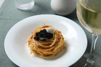 Photo of Tasty spaghetti with tomato sauce and black caviar served on table, closeup. Exquisite presentation of pasta dish