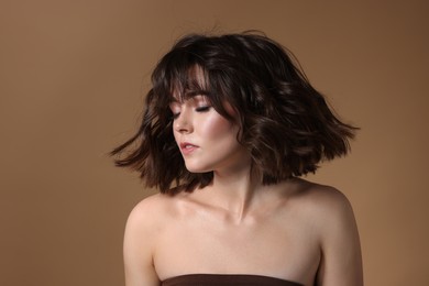 Photo of Portrait of beautiful young woman with wavy hairstyle on brown background