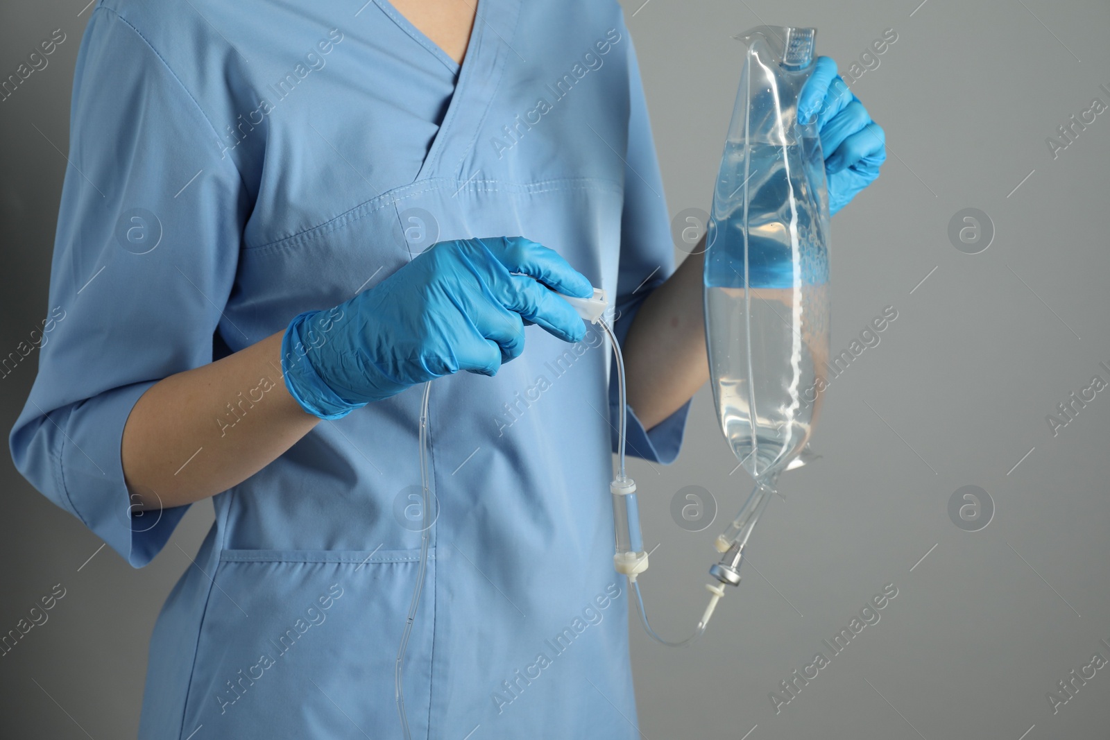 Photo of Nurse with IV infusion set on grey background, closeup