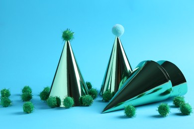 Party hats with green pompoms on light blue background