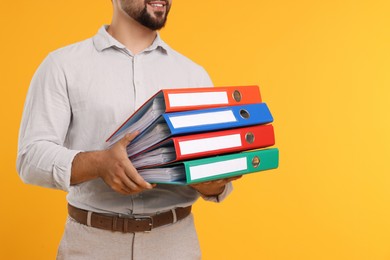 Photo of Man with folders on orange background, closeup. Space for text