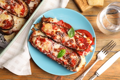 Photo of Baked eggplant with tomatoes, cheese and basil served on wooden table, flat lay