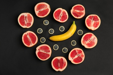 Photo of Flat lay composition with condoms and exotic fruits on black background. Erotic concept