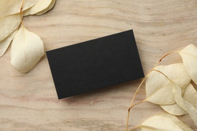 Photo of Blank business card and beige leaves on wooden table, flat lay. Mockup for design