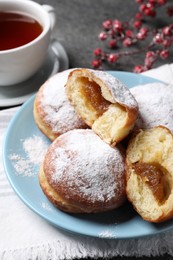 Photo of Delicious sweet buns with jam and cup of tea on table, closeup