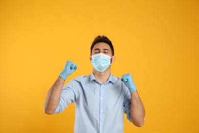 Emotional man with protective mask and gloves on yellow background. Strong immunity concept