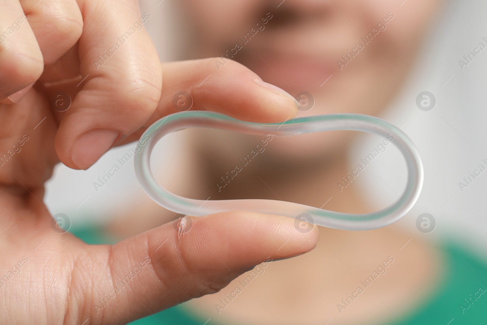 Photo of Woman holding diaphragm vaginal contraceptive ring on blurred background, closeup