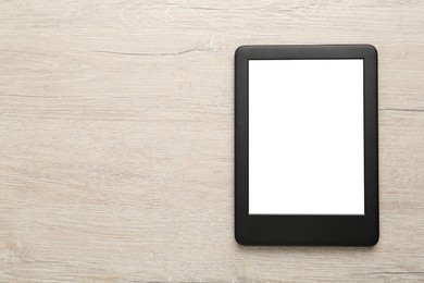 Photo of Modern e-book reader with blank screen on white wooden table, top view. Space for text