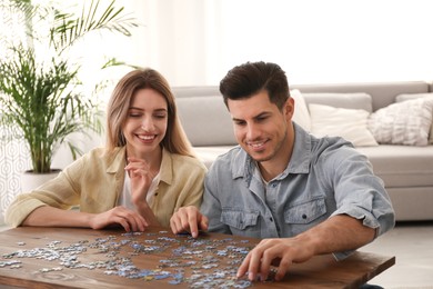 Happy couple playing with puzzles at home