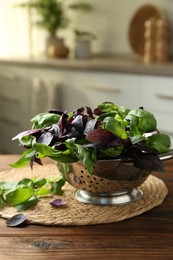 Metal colander with different fresh basil leaves on wooden table in kitchen