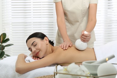 Young woman receiving herbal bag massage in spa salon