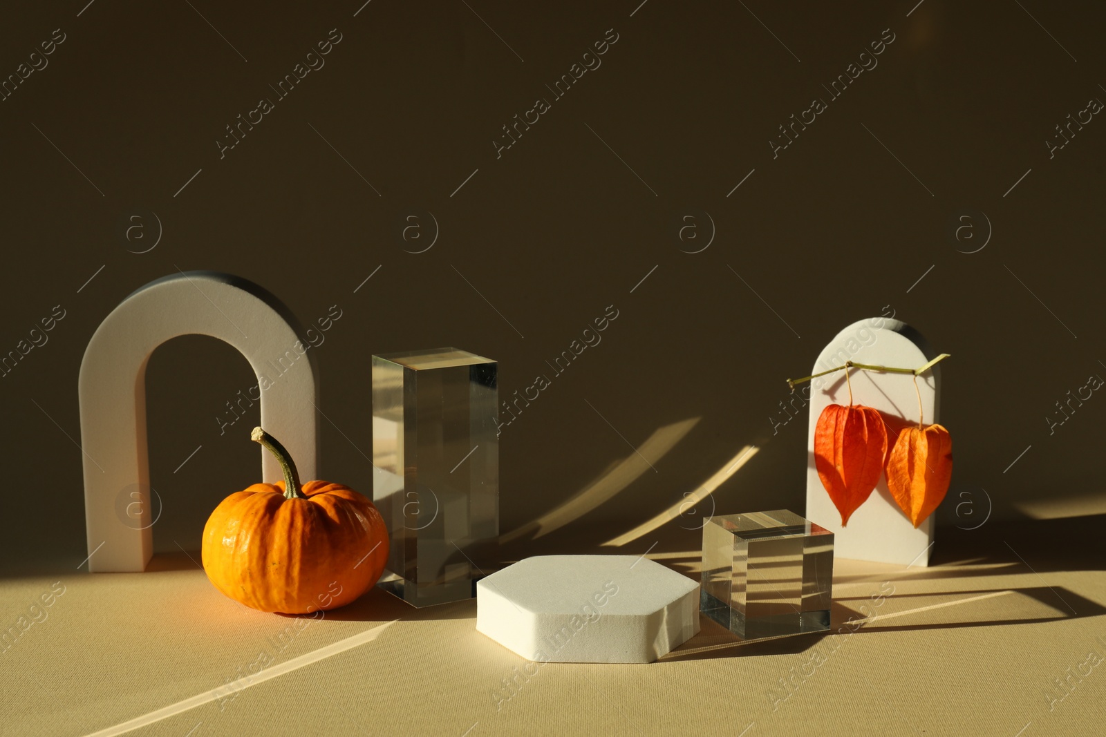 Photo of Stylish presentation for product. Autumn composition with decorative pumpkin and geometric figures on beige background