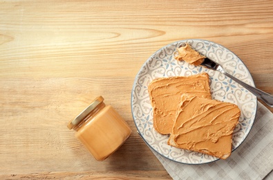 Photo of Jar with creamy peanut butter and toasts on plate