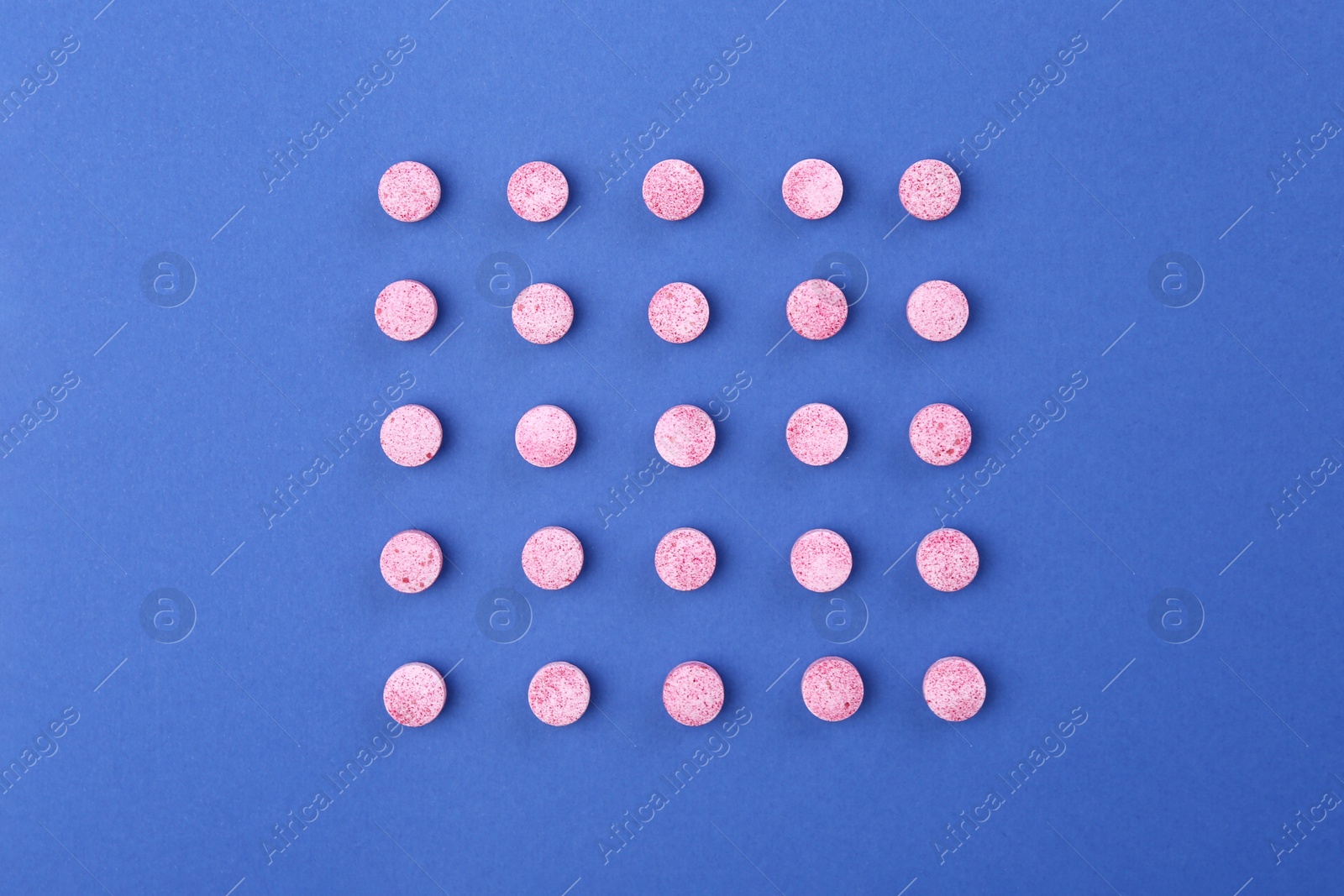 Photo of Many pink vitamin pills on blue background, flat lay