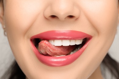 Photo of Woman showing her tongue on light background, closeup