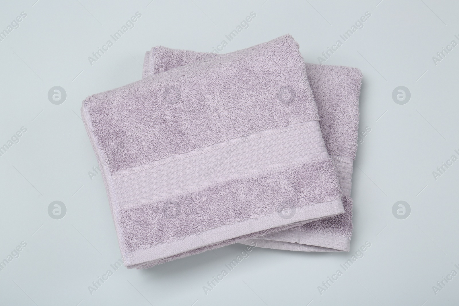 Photo of Violet terry towels on light grey background, top view