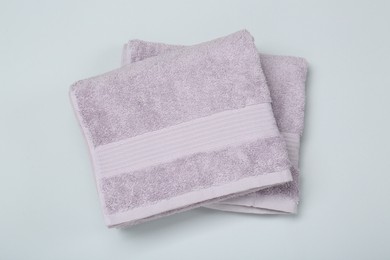 Photo of Violet terry towels on light grey background, top view