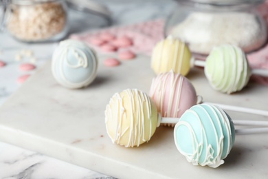 Photo of Sweet cake pops on white marble table, closeup