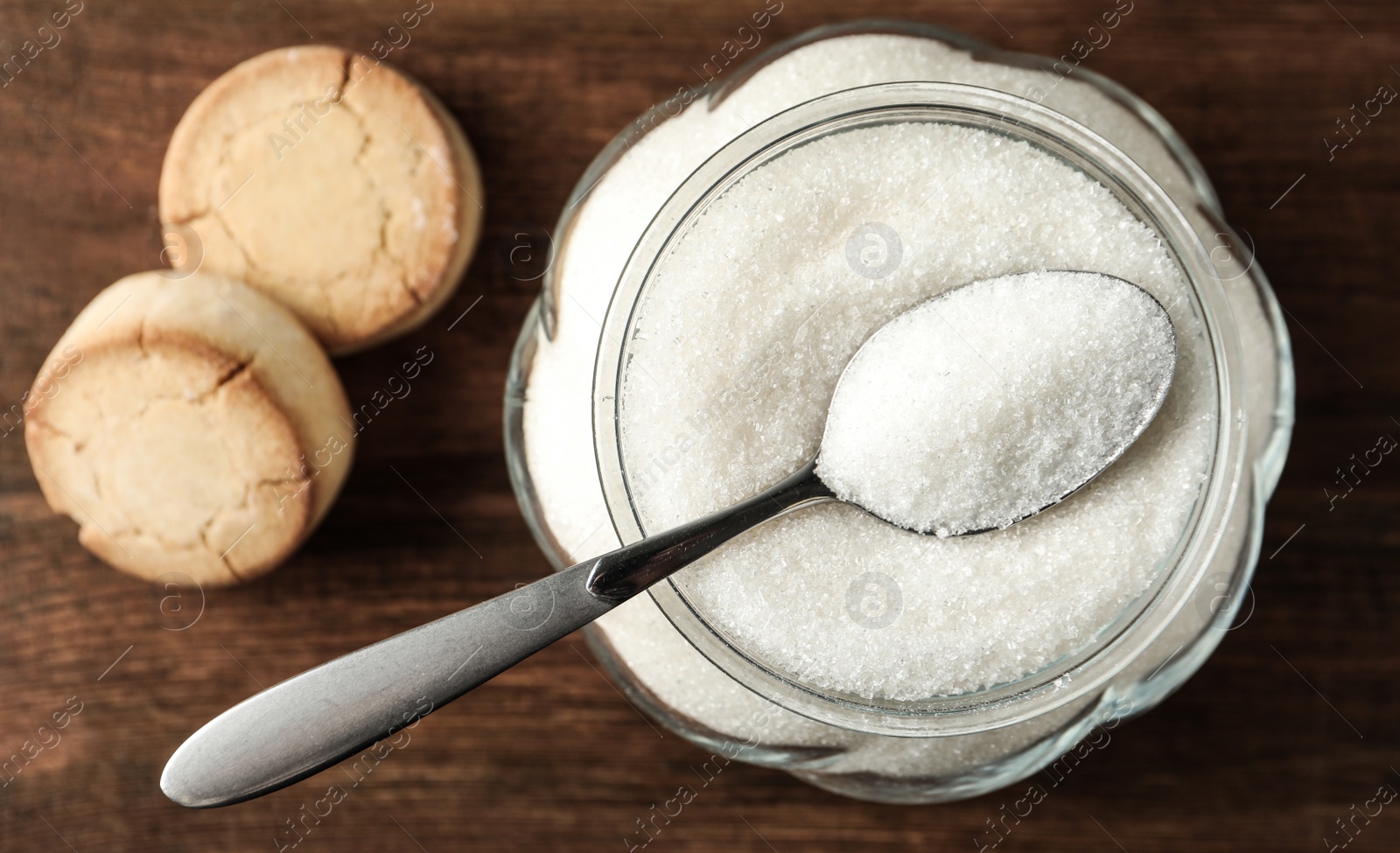 Photo of Glass bowl with sugar and cookies on wooden table, flat lay