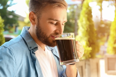 Photo of Handsome man with cold kvass outdoors. Traditional Russian summer drink