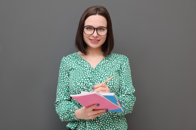 Photo of Happy young intern with notebooks and pen on grey background