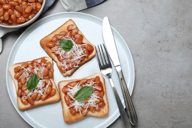 Photo of Toasts with delicious canned beans on light grey table, flat lay. Space for text