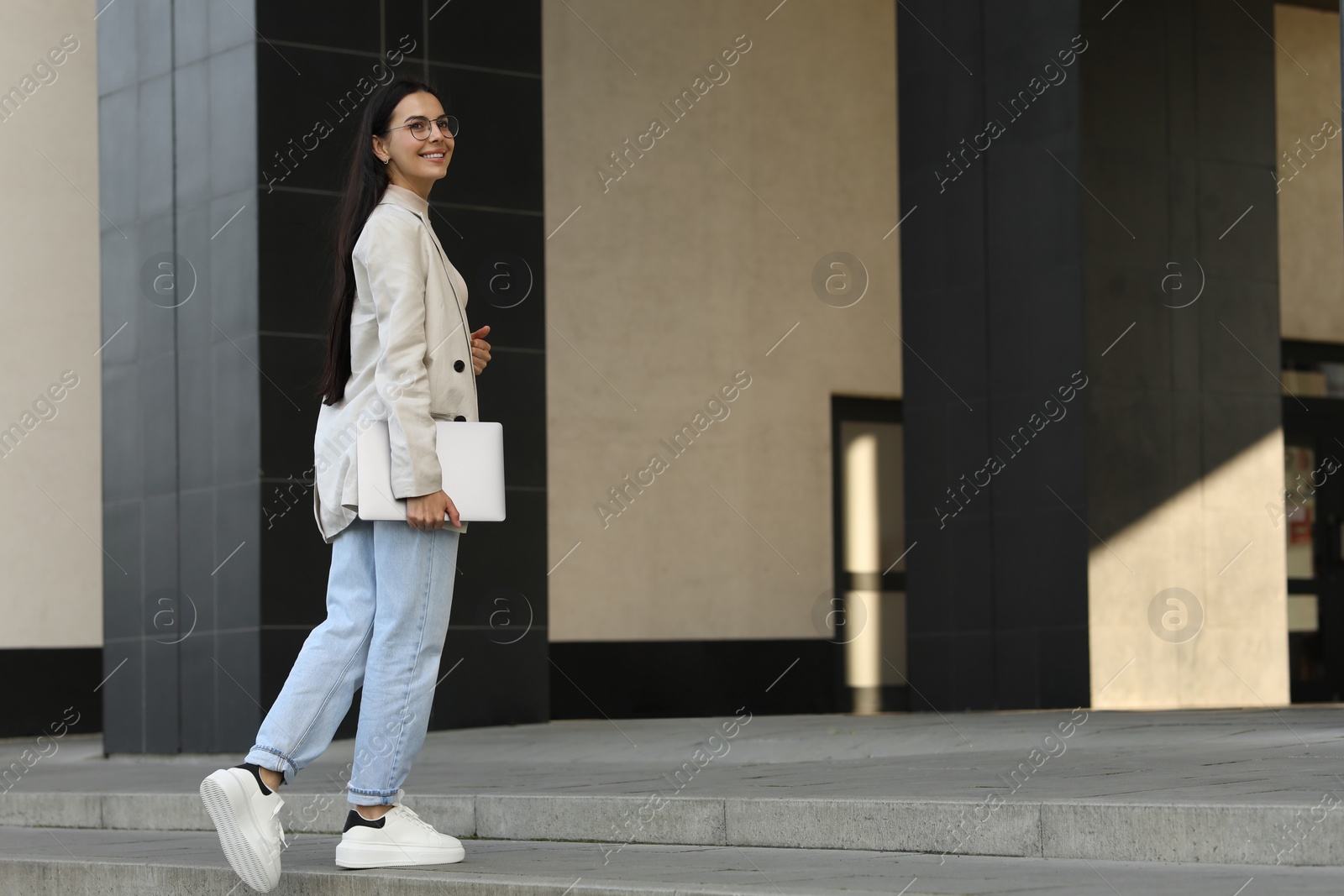 Photo of Happy young woman holding modern laptop outdoors. Space for text