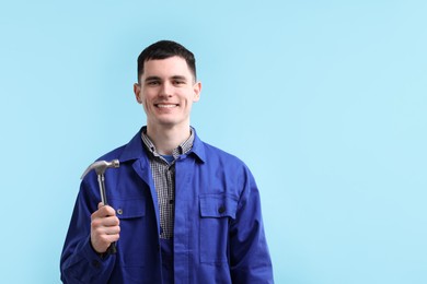 Photo of Professional repairman holding hammer on light blue background. Space for text