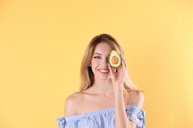 Portrait of young beautiful woman with ripe delicious avocado on color background