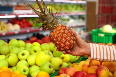 Photo of Woman choosing fruits during shopping in supermarket, closeup