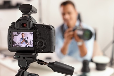 Photo of Photo blogger recording video indoors, selective focus on camera display. Space for text