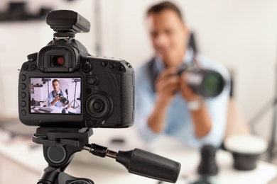 Photo blogger recording video indoors, selective focus on camera display. Space for text