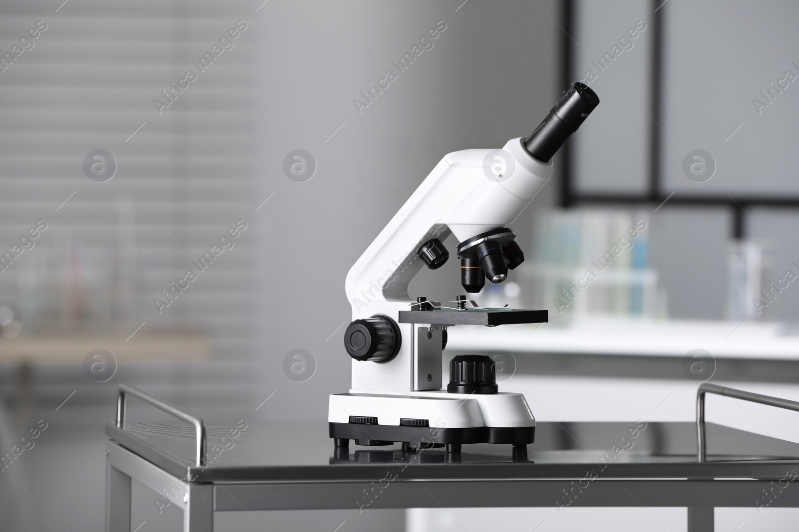 Photo of Modern medical microscope on metal table in laboratory, space for text