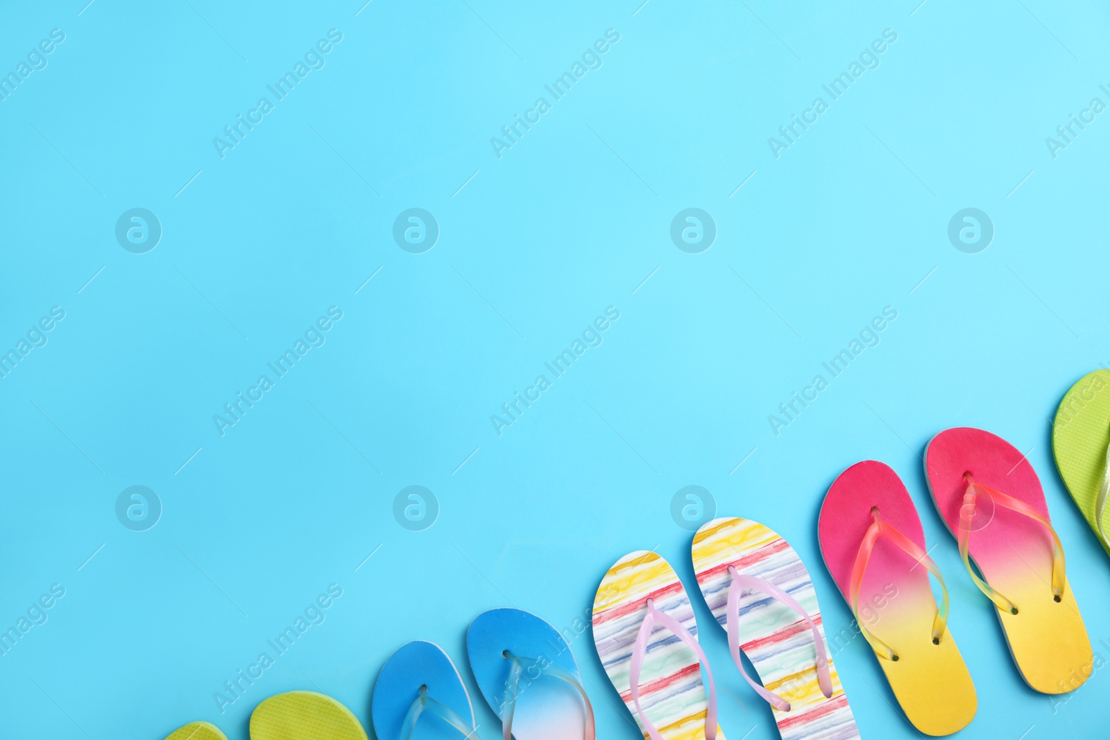 Photo of Different flip flops and space for text on blue background, flat lay. Summer beach accessories