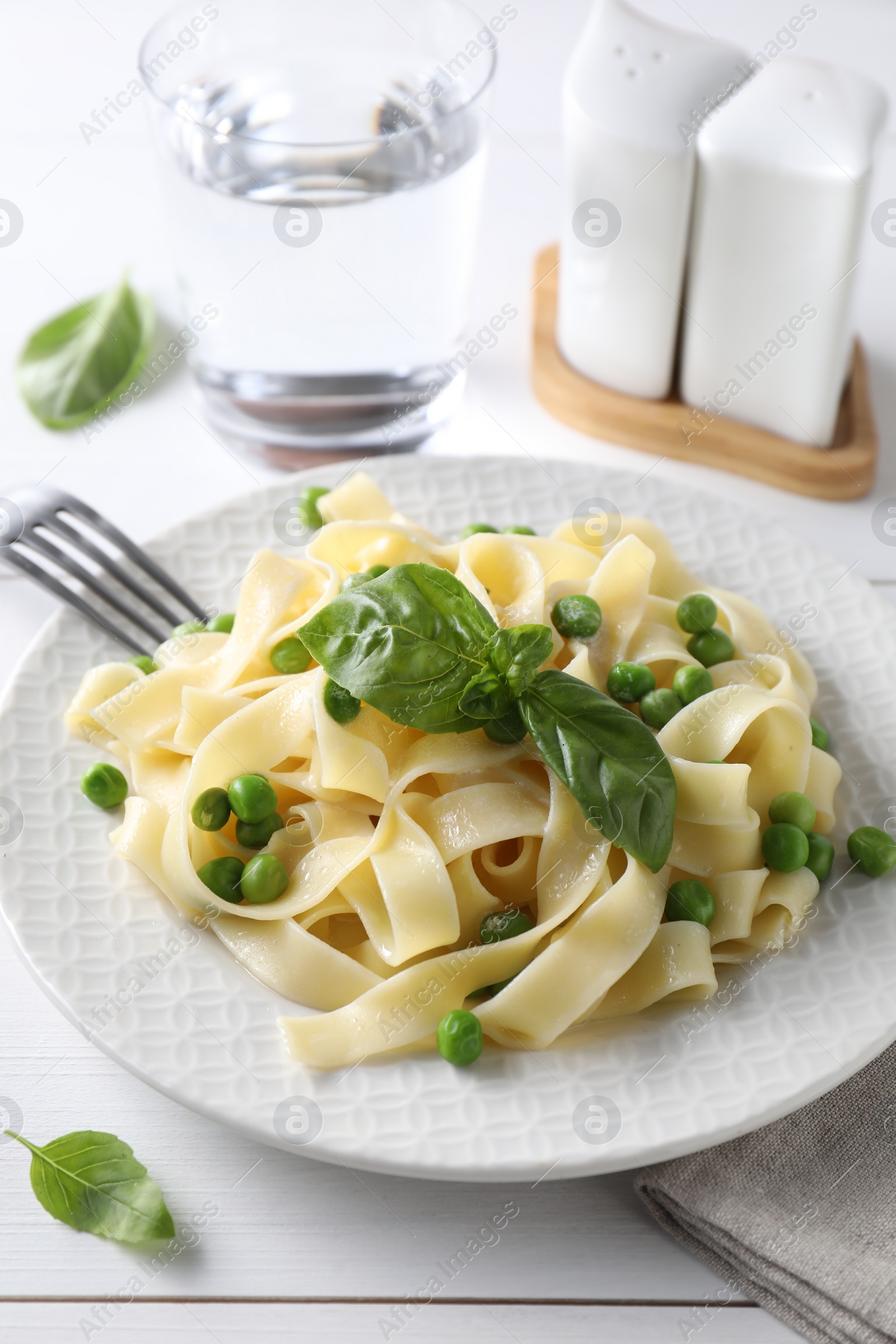 Photo of Delicious pasta with green peas served on white wooden table