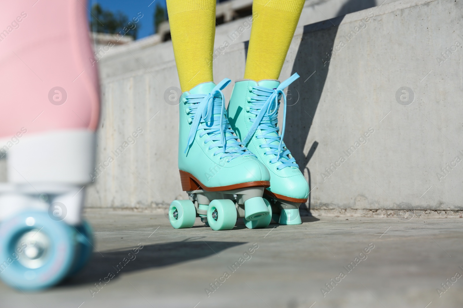 Photo of Young woman with retro roller skates in city on sunny day, closeup