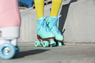 Young woman with retro roller skates in city on sunny day, closeup