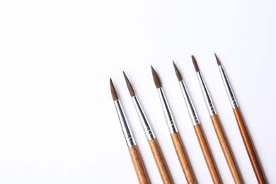 Photo of Different paint brushes on white background, top view. Space for text