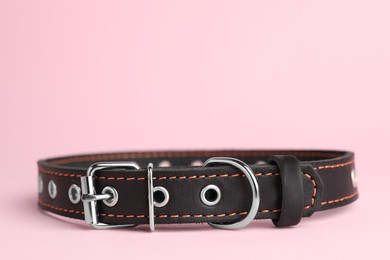 Photo of Black leather dog collar on pink background, closeup. Space for text